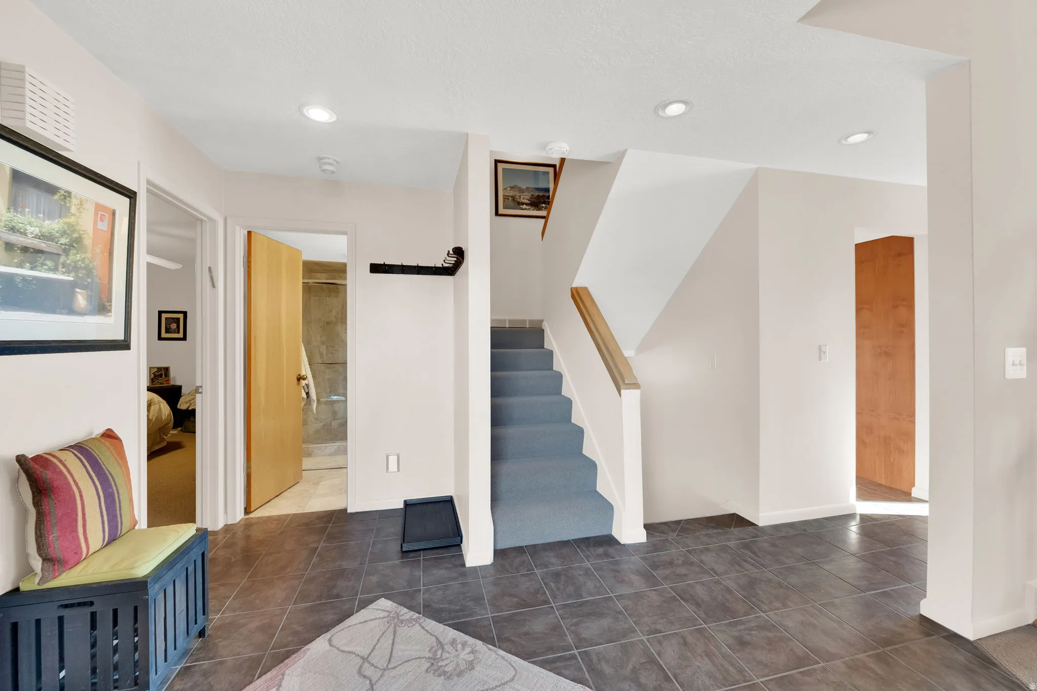 Entryway featuring dark tile flooring, a carpeted staircase with a wood handrail, and recessed lighting