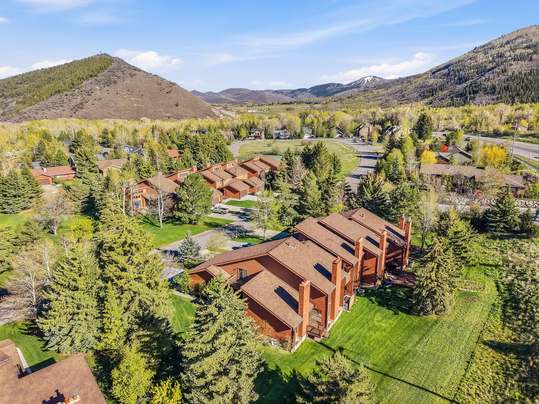 Aerial perspective showcasing multiple townhouse-style properties featuring brown exteriors and brown shingle roofs