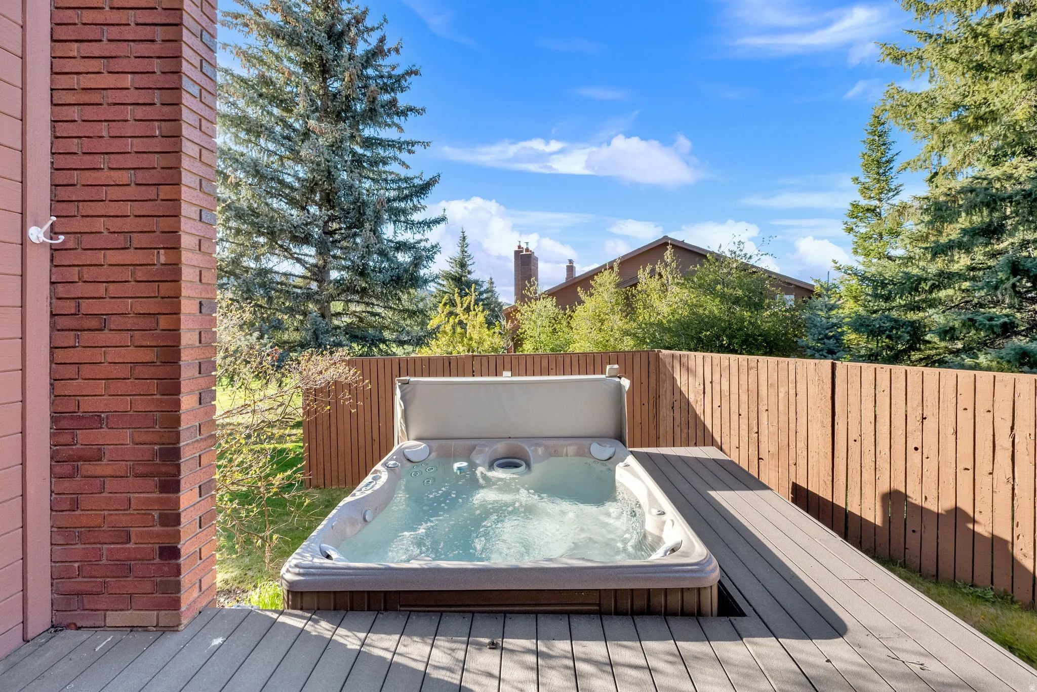 Outdoor hot tub on a composite deck, bordered by a wood privacy fence