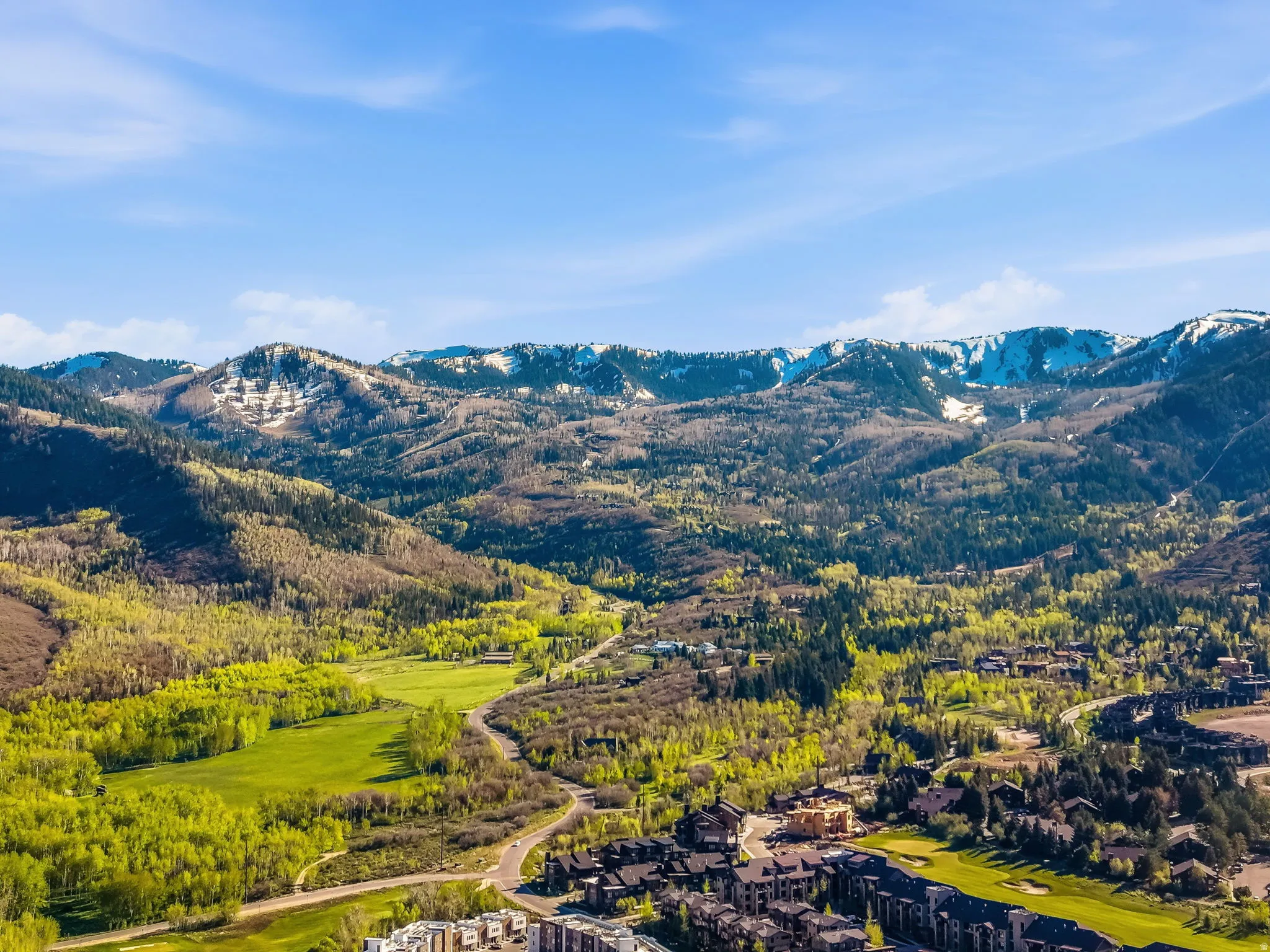 Expansive mountain landscape featuring snow-capped peaks and verdant valleys