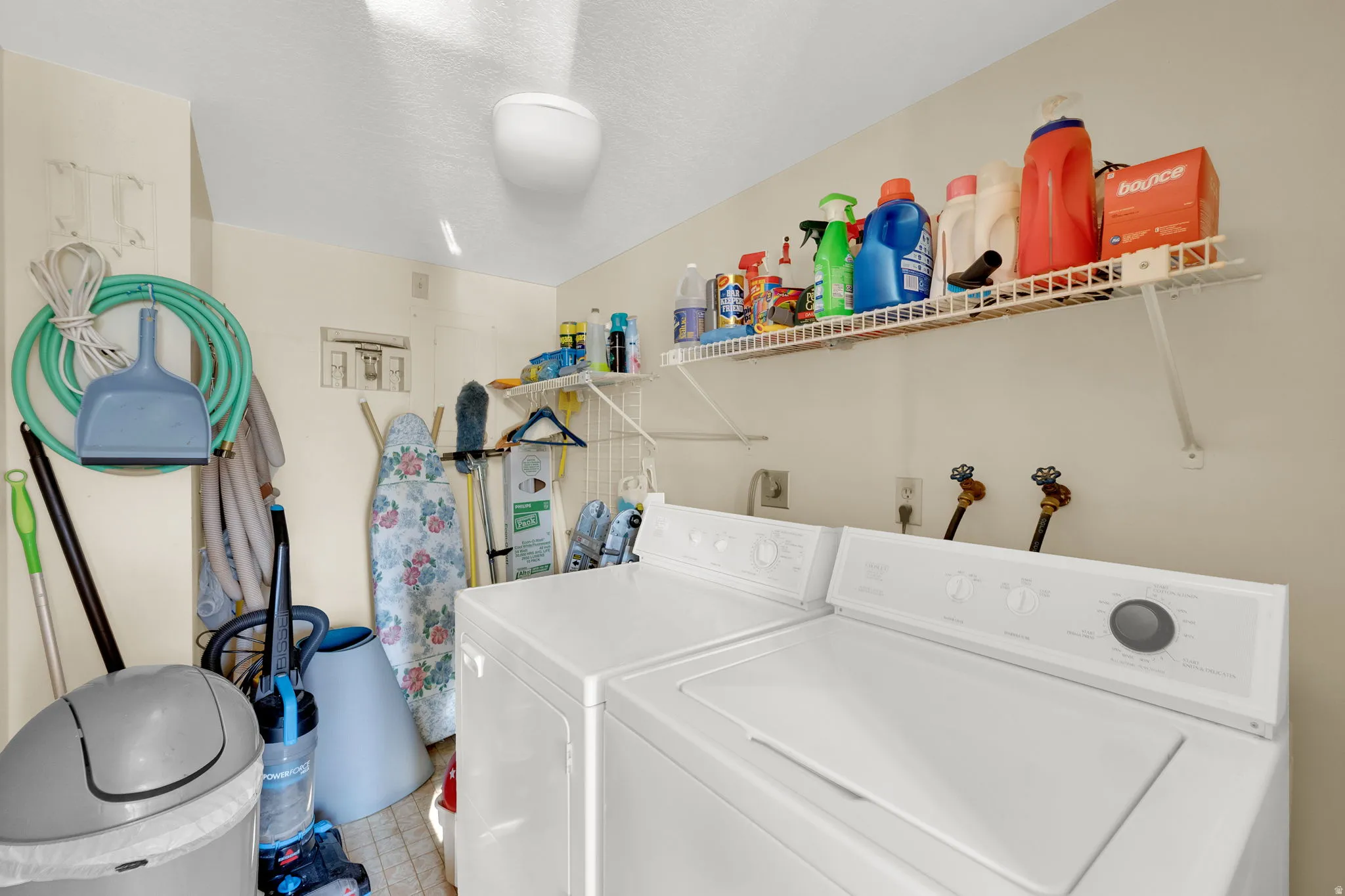 Dedicated utility area featuring a washer and dryer hookup, overhead wire shelving, and neutral wall tones