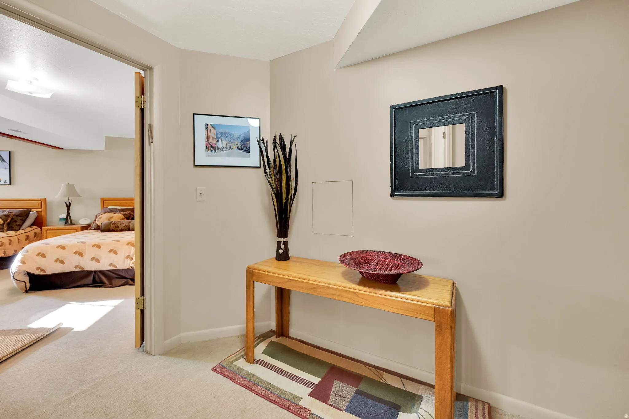 Neutral-toned hallway with carpet flooring and a door opening to a carpeted room