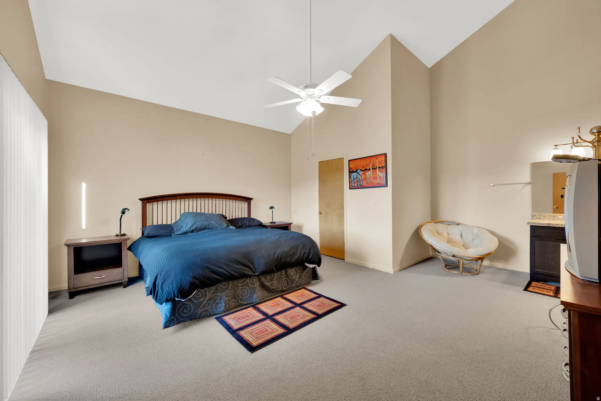 Spacious bedroom featuring vaulted ceilings, neutral-toned walls, and plush carpeting
