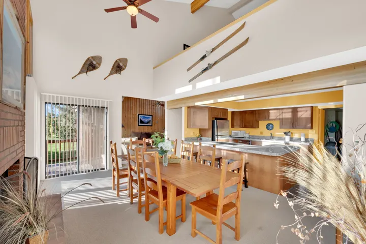 Spacious living area featuring a vaulted ceiling with exposed beams and a ceiling fan