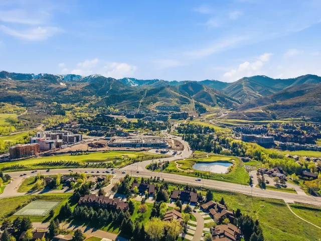 Expansive mountain setting featuring diverse architectural styles, a golf course with a pond, paved roadways, and surrounding natural landscapes