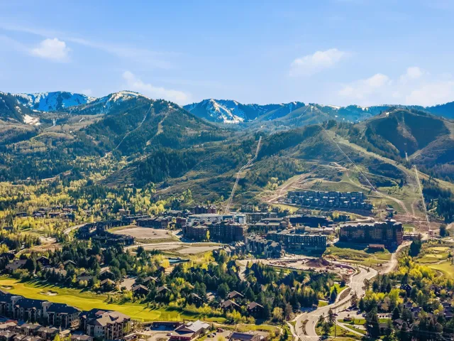 Expansive mountain landscape featuring snow-capped peaks and forested slopes