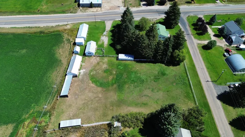 Expansive undeveloped land featuring multiple outbuildings, mature trees, and direct road frontage