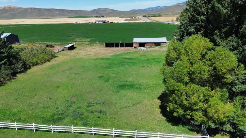 Expansive green pasture with a white rail fence