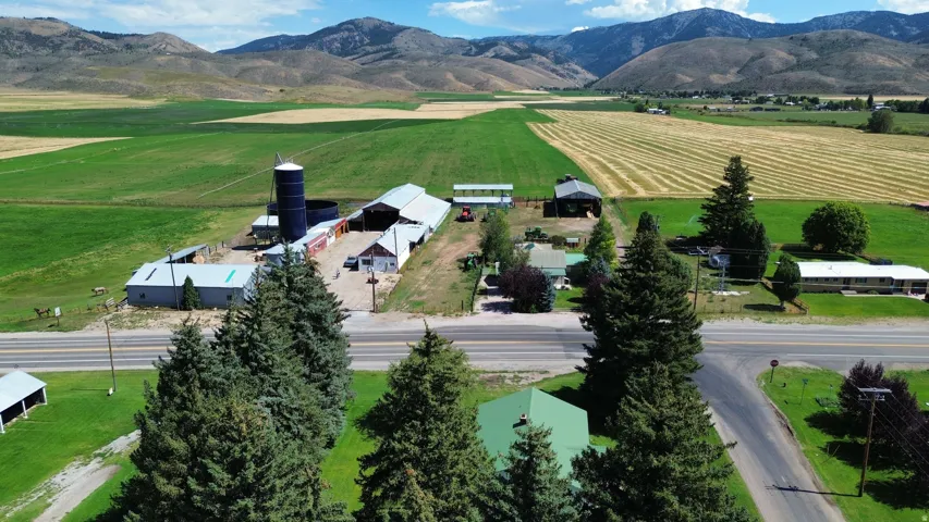 Expansive rural property featuring multiple outbuildings, open fields, and mountain backdrops