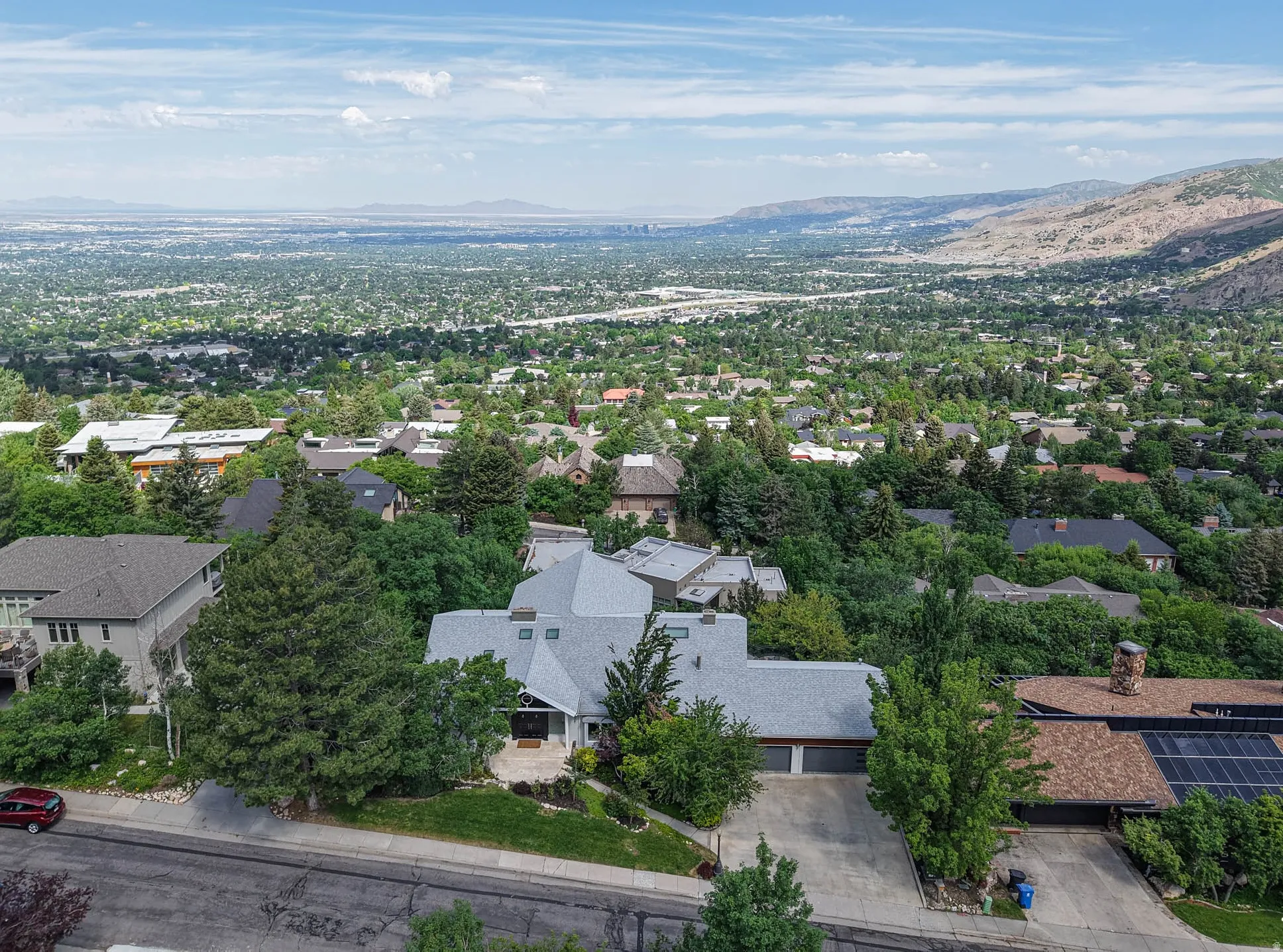 Expansive aerial perspective showcasing a residential property with a multi-car driveway, mature landscaping, and a pitched roofline