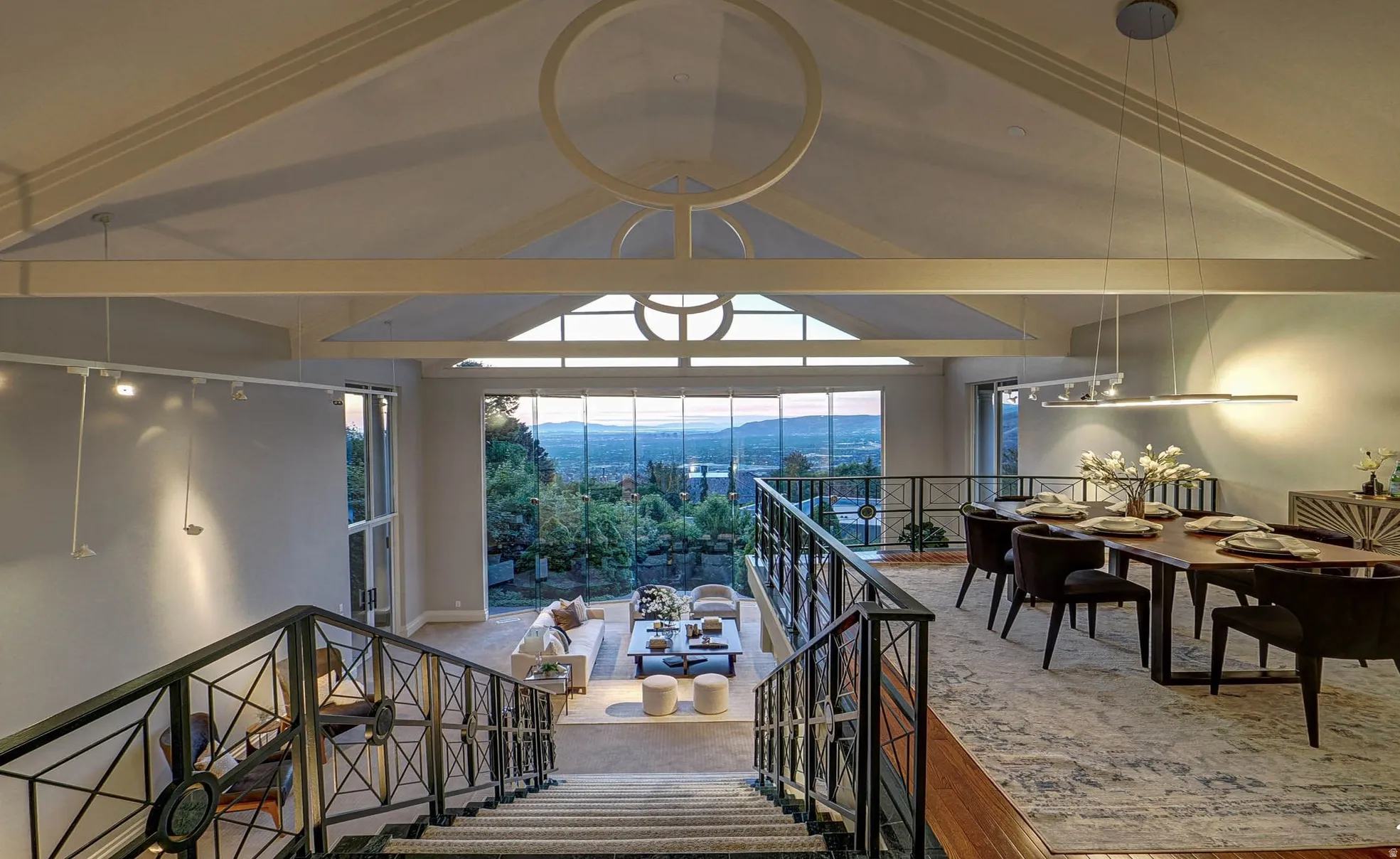 Multi-level interior featuring a grand staircase with wrought iron railings, a vaulted ceiling, floor-to-ceiling windows, and wood-finish flooring