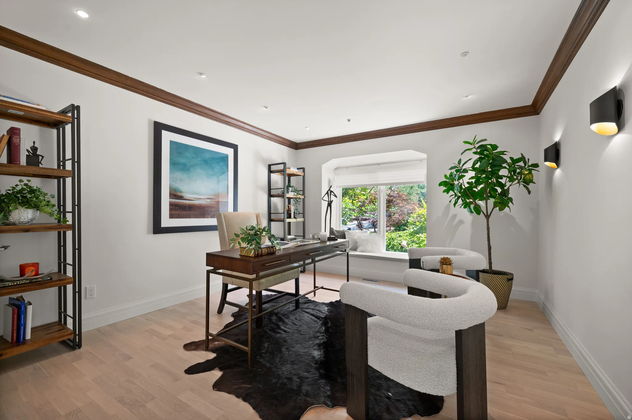 Bright room featuring light wood-finish flooring, white walls, and dark wood crown molding