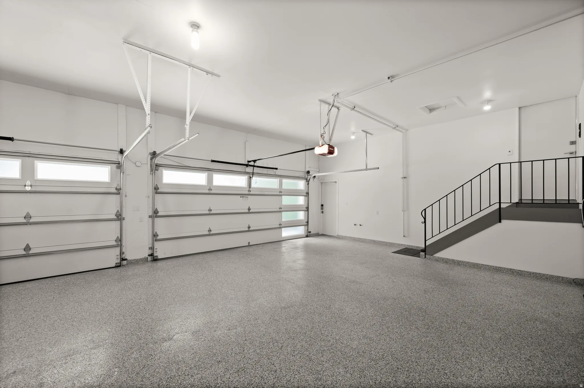 Spacious two-car garage featuring a speckled epoxy floor, white walls, and bright overhead lighting