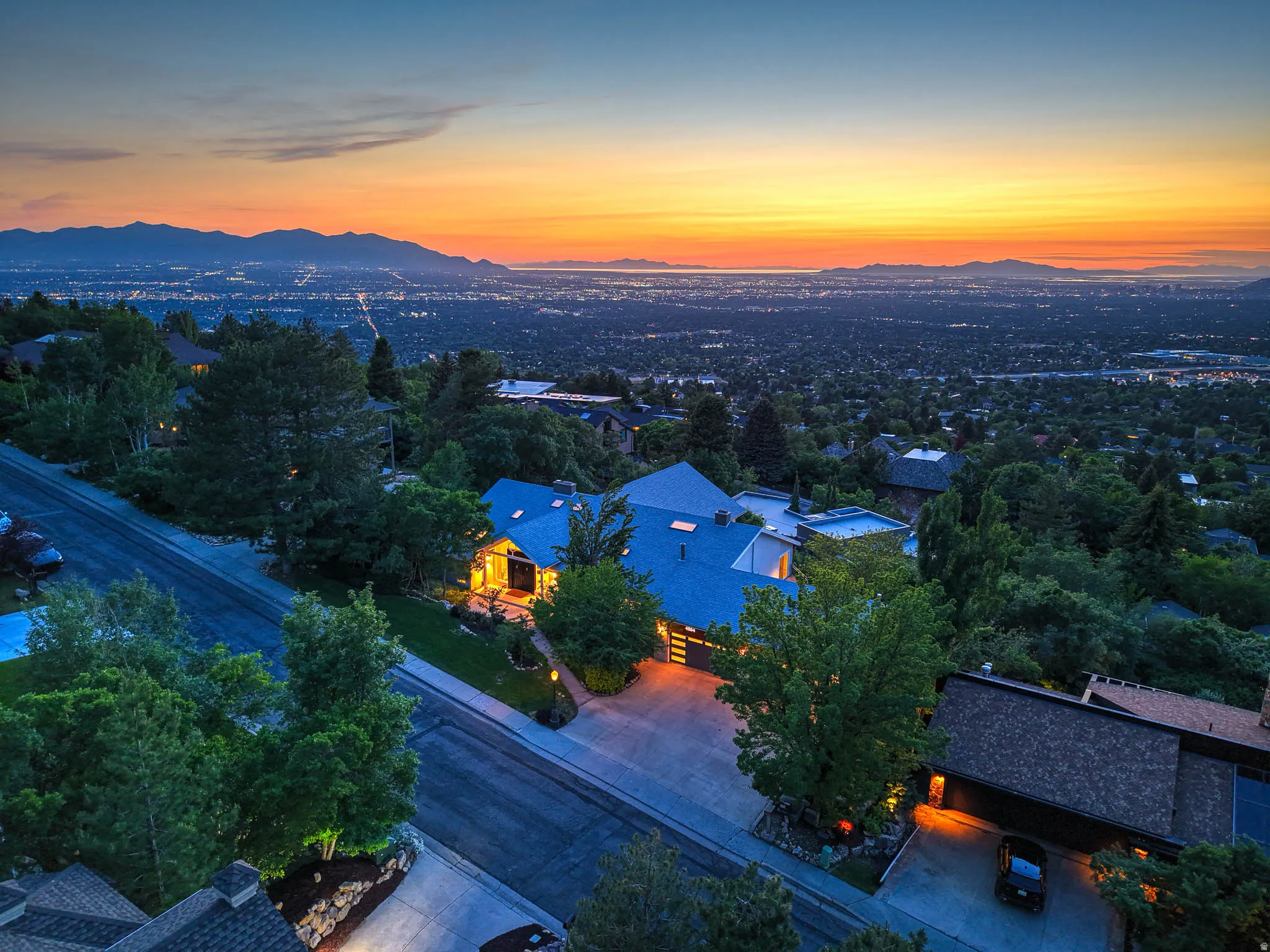 Aerial perspective featuring a residential property with a multi-level roofline and surrounding mature landscaping