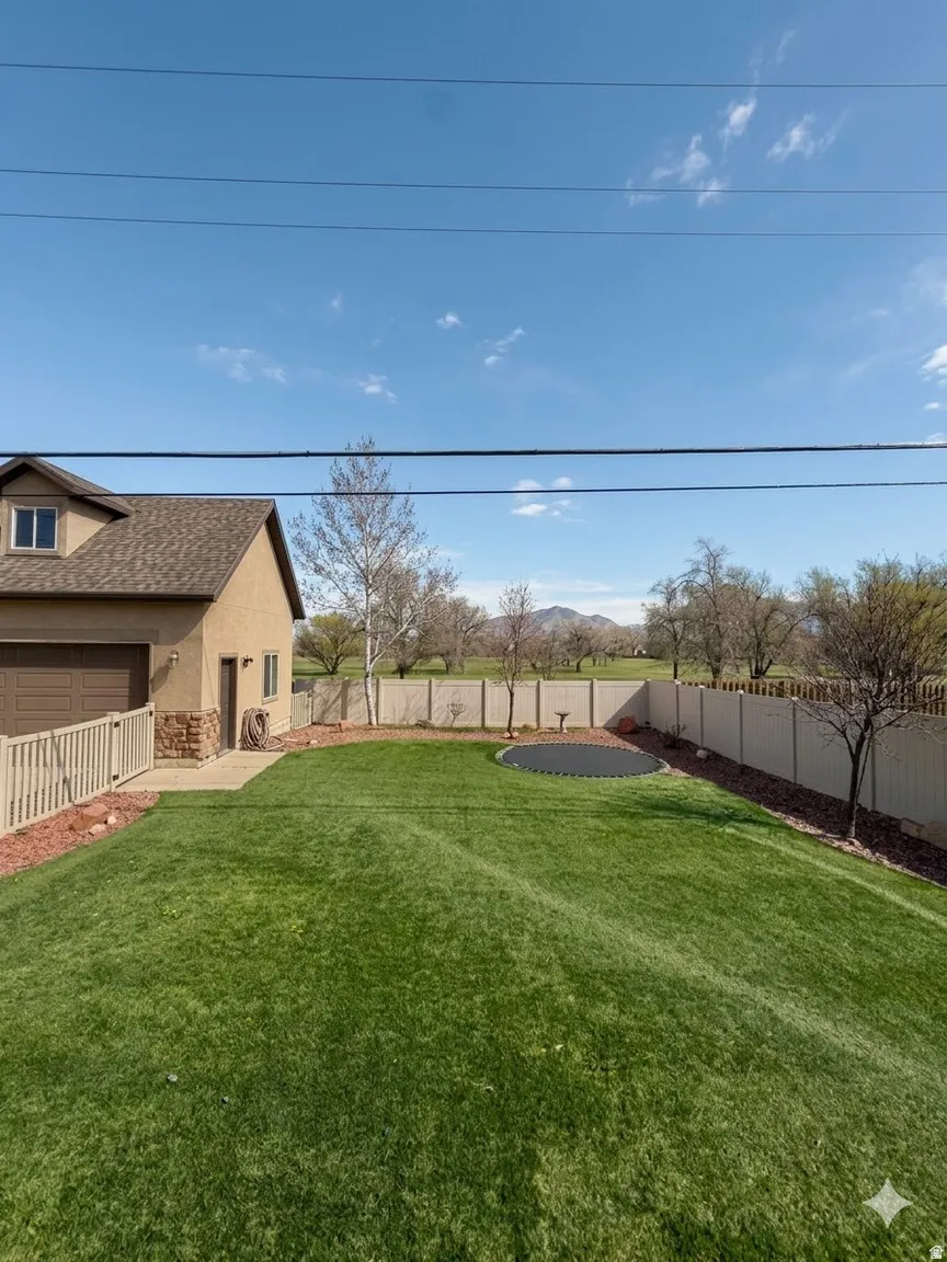 View of fenced backyard with Xeroscaping and trampoline