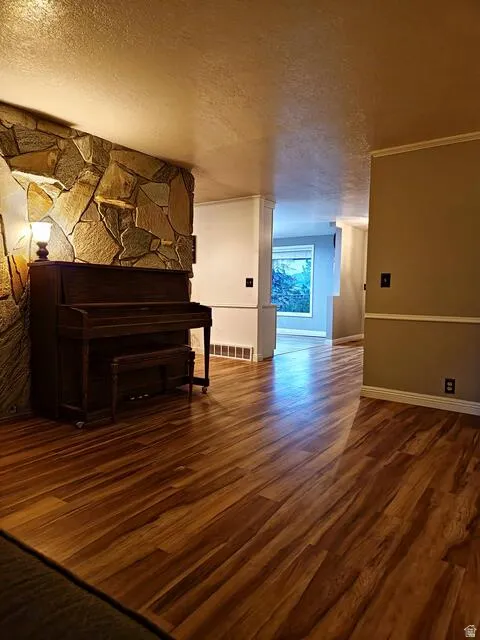 Interior space featuring wood-finish flooring, a stone-clad wall accent, and white baseboards