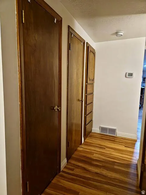 Hallway with wood-finish flooring and multiple built-in storage options