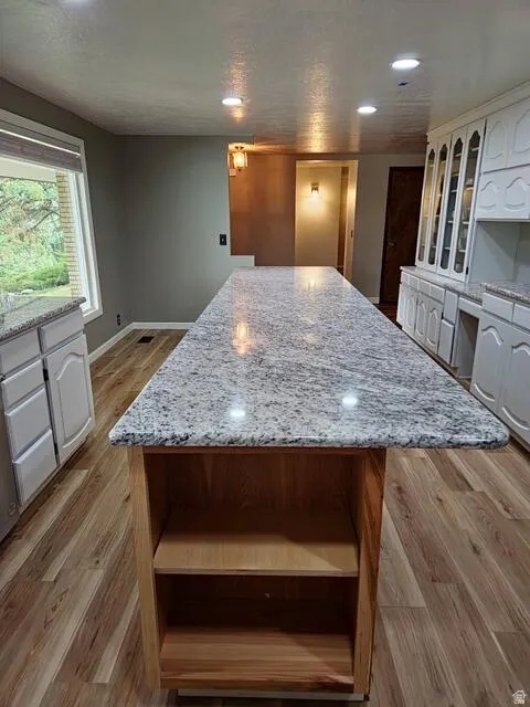 Expansive kitchen island featuring a light-toned granite countertop and natural wood-finish base with open shelving