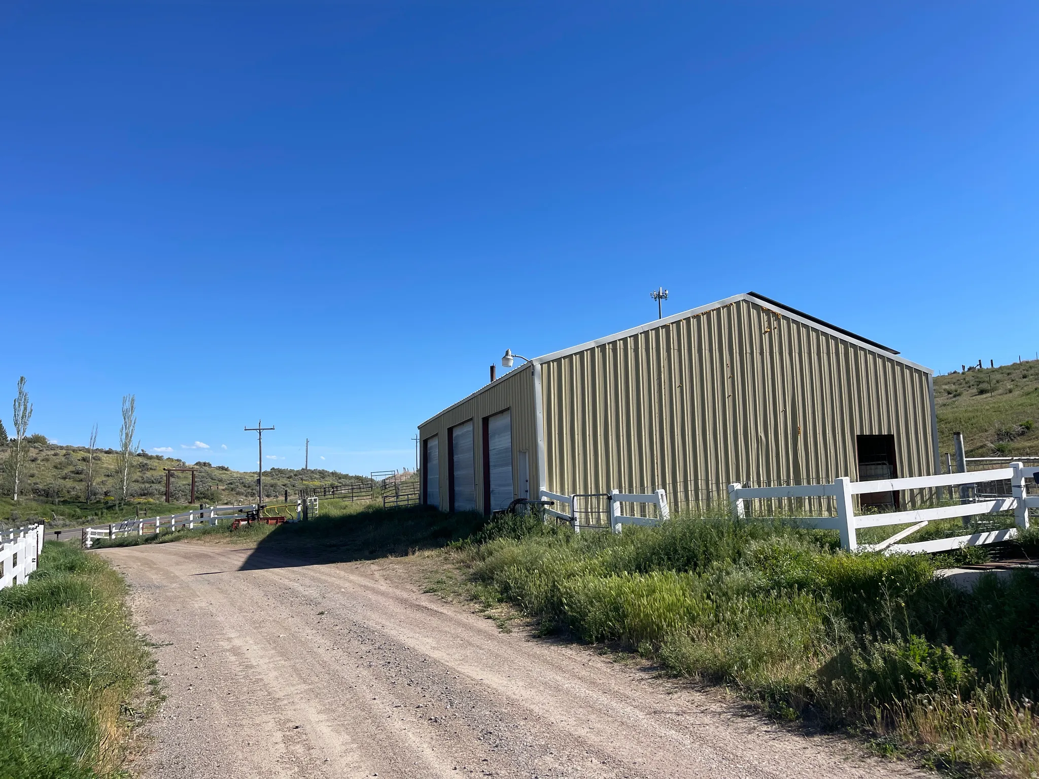 Corrugated metal building with three bay doors, a sloped roof, and an additional entry