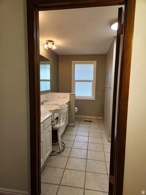 Bathroom featuring a dual vanity with white cabinetry, light-toned countertop, and dual sinks