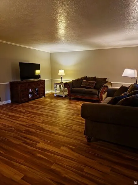 Spacious room featuring wood-finish flooring, neutral-toned walls, and white crown molding