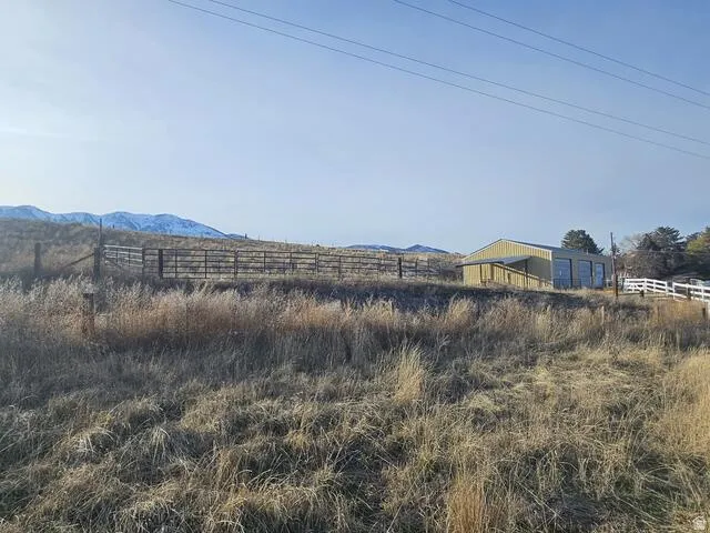 Expansive open field with a metal-sided utility building featuring multiple bay doors