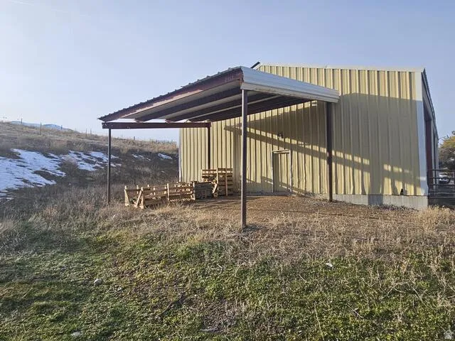 Metal-sided structure with a covered lean-to, a concrete foundation, and a single exterior door