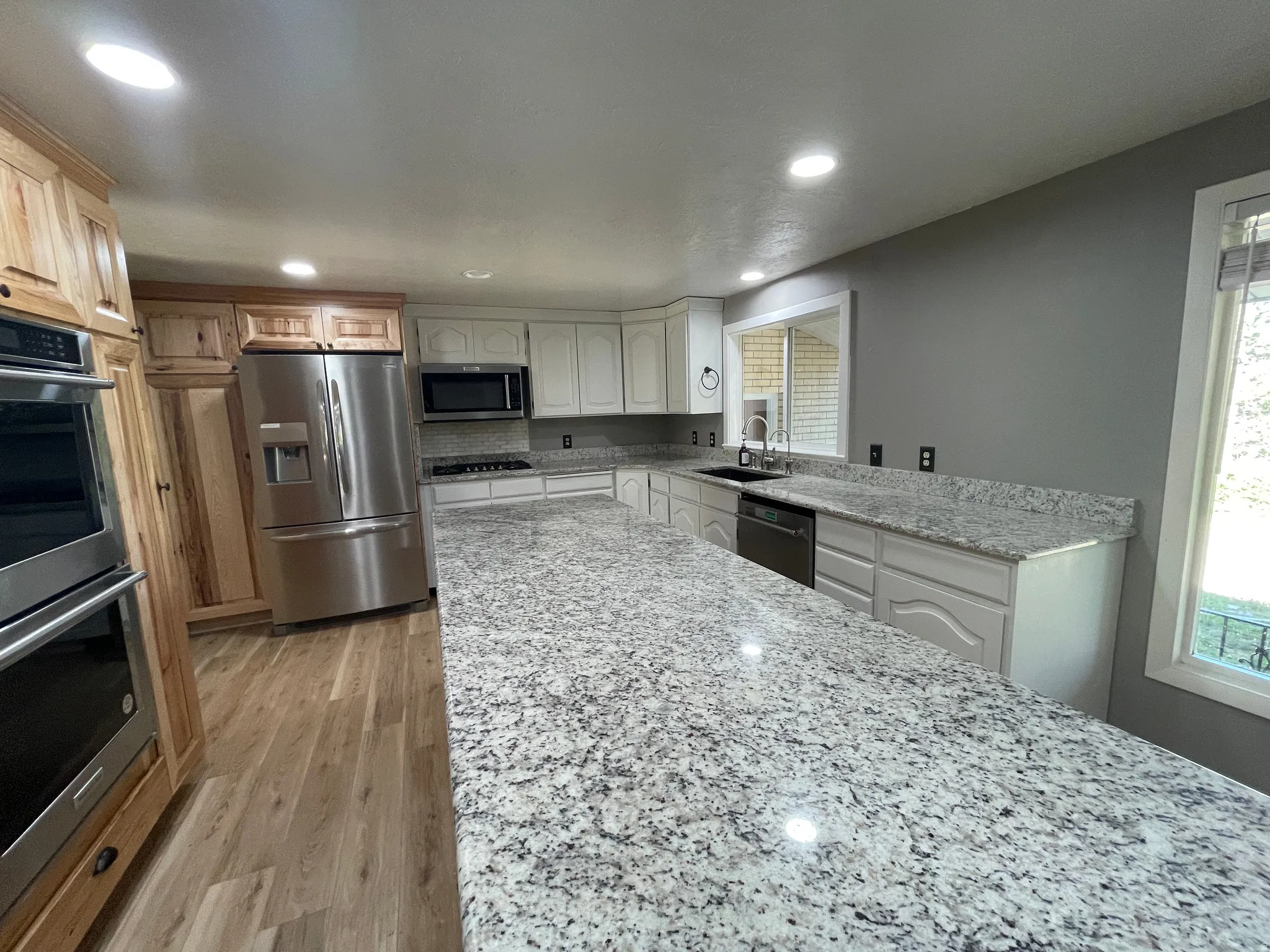 Spacious kitchen featuring extensive granite countertops, light wood-finish flooring, and recessed lighting
