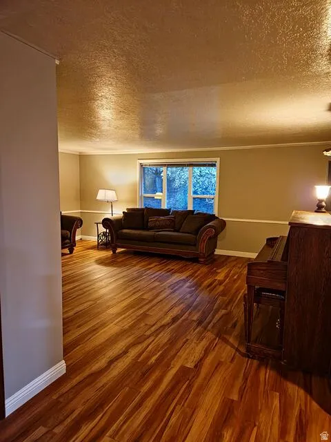 Spacious interior room featuring wood-finish flooring, neutral wall paint, and white baseboards