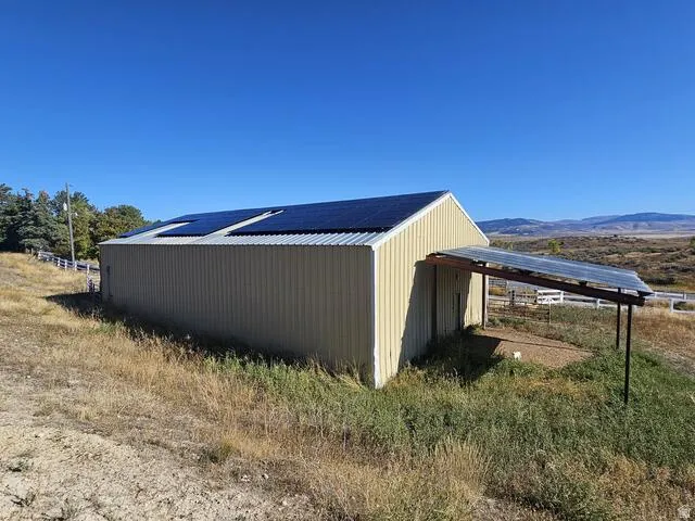Corrugated metal barn with roof-mounted solar panels and an attached covered lean-to structure