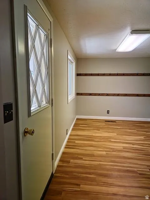 Entryway featuring a decorative glass-paned door, wood-finish flooring, and built-in wall hooks