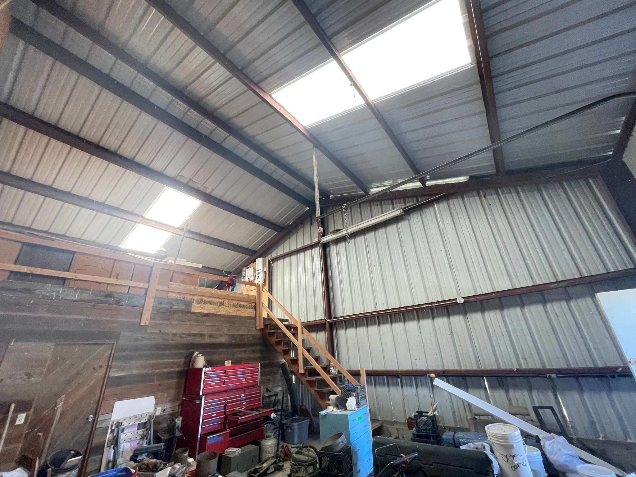Metal structure featuring a high ceiling, exposed beams, and multiple skylights