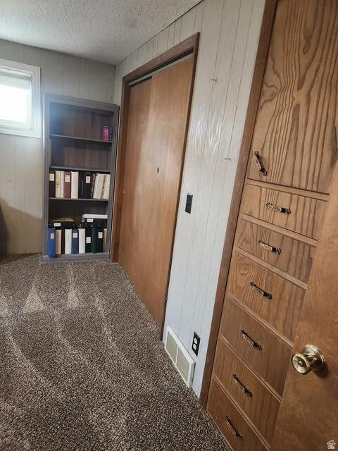 Carpeted room featuring a built-in wooden dresser with multiple drawers, a sliding closet door, and a built-in bookshelf