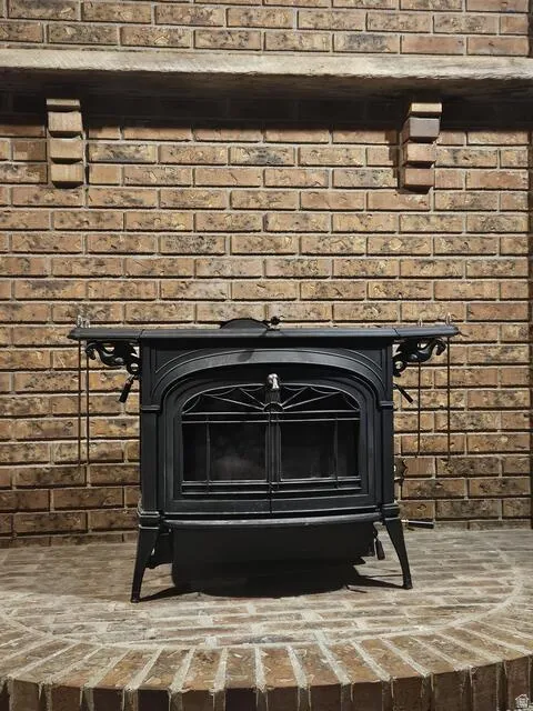 Cast iron wood-burning stove with intricate detailing, set against a full brick wall with a stone mantel