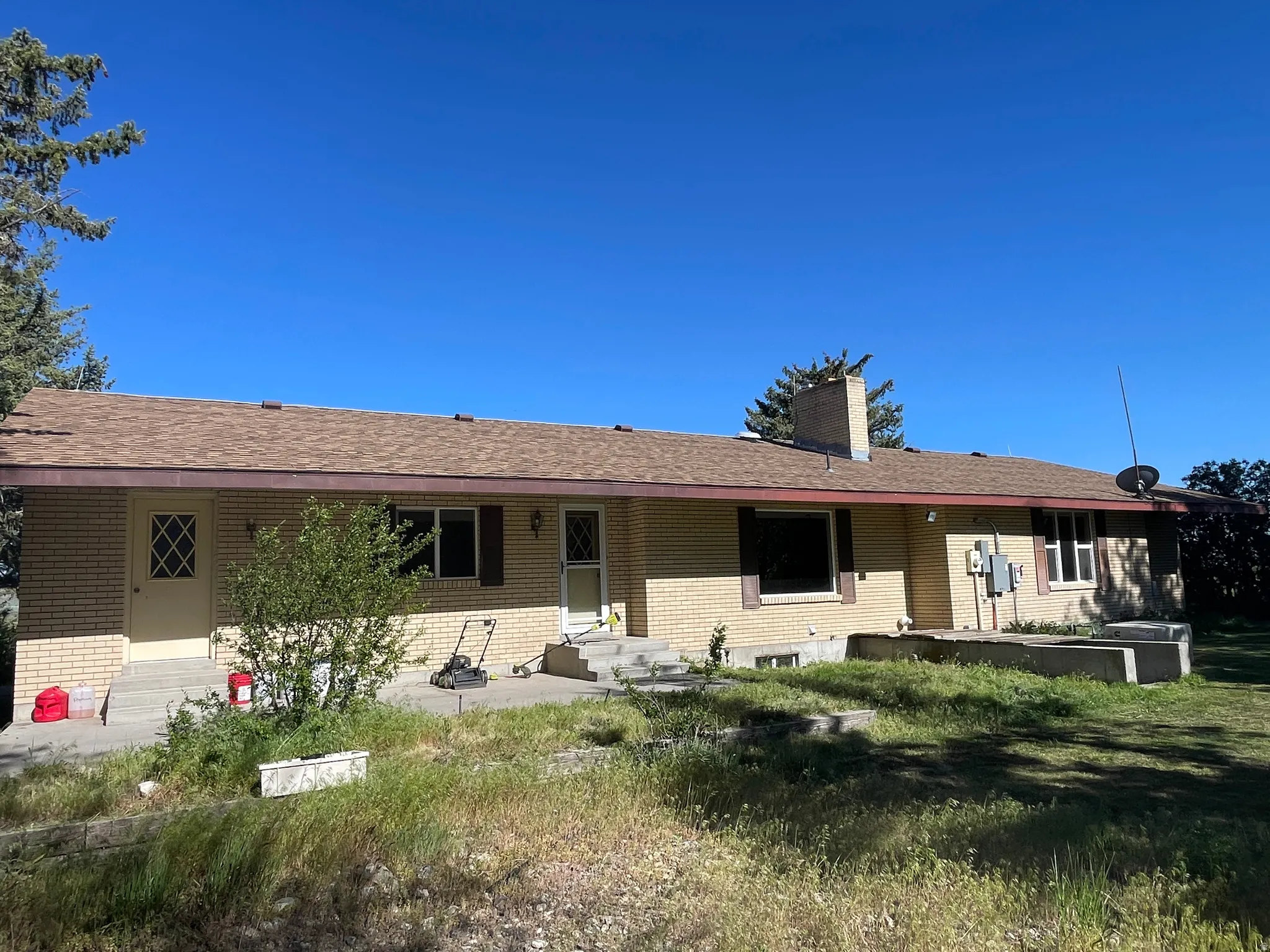 Ranch-style exterior featuring a light brick facade and a brown shingle roof