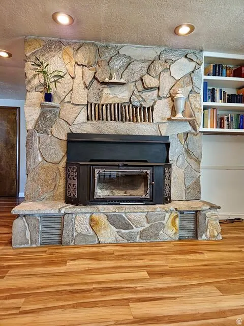 Floor-to-ceiling stone fireplace featuring a dark-toned wood-burning insert