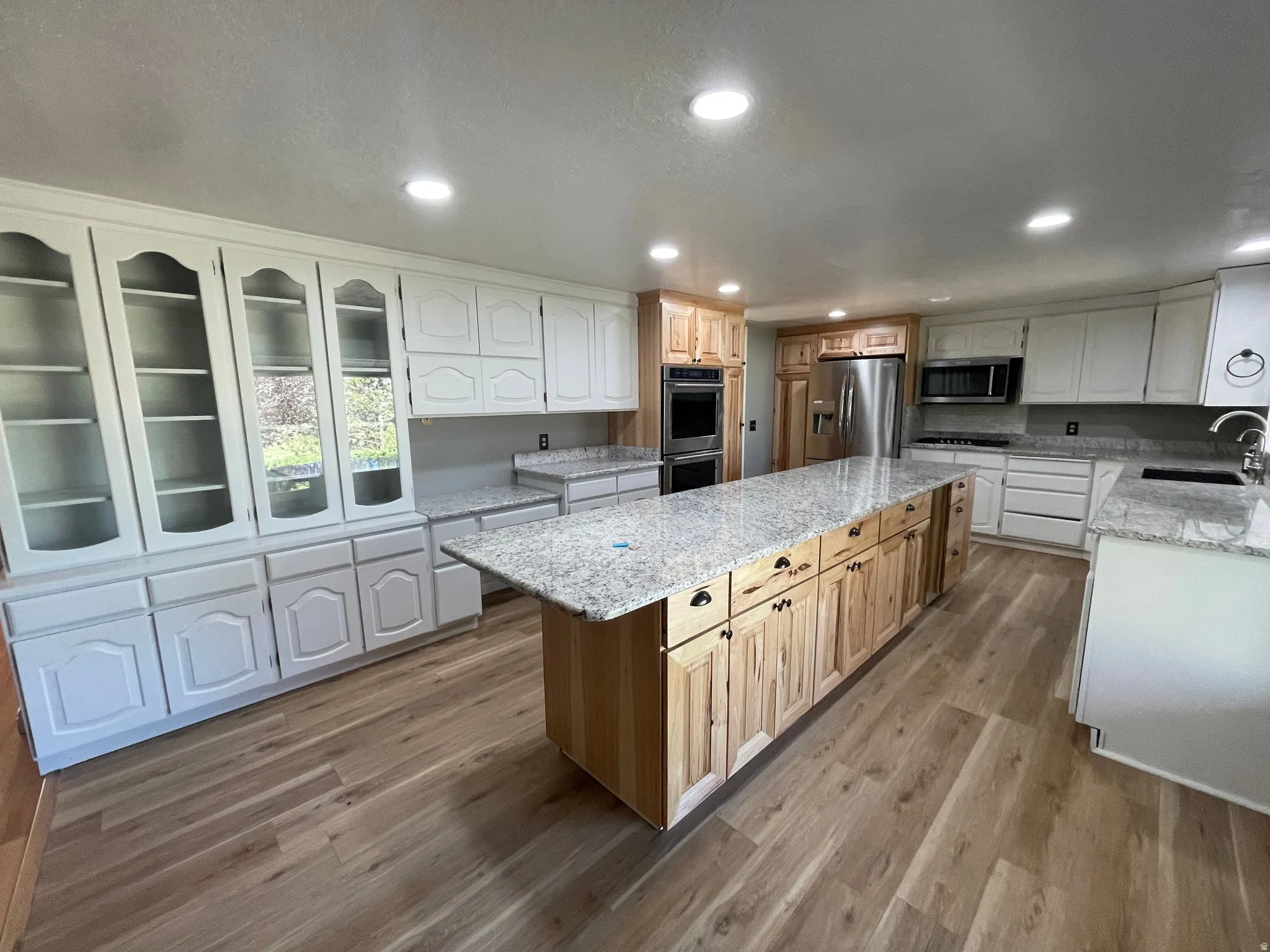 Spacious kitchen featuring a large central island with natural wood cabinetry and a light-toned countertop