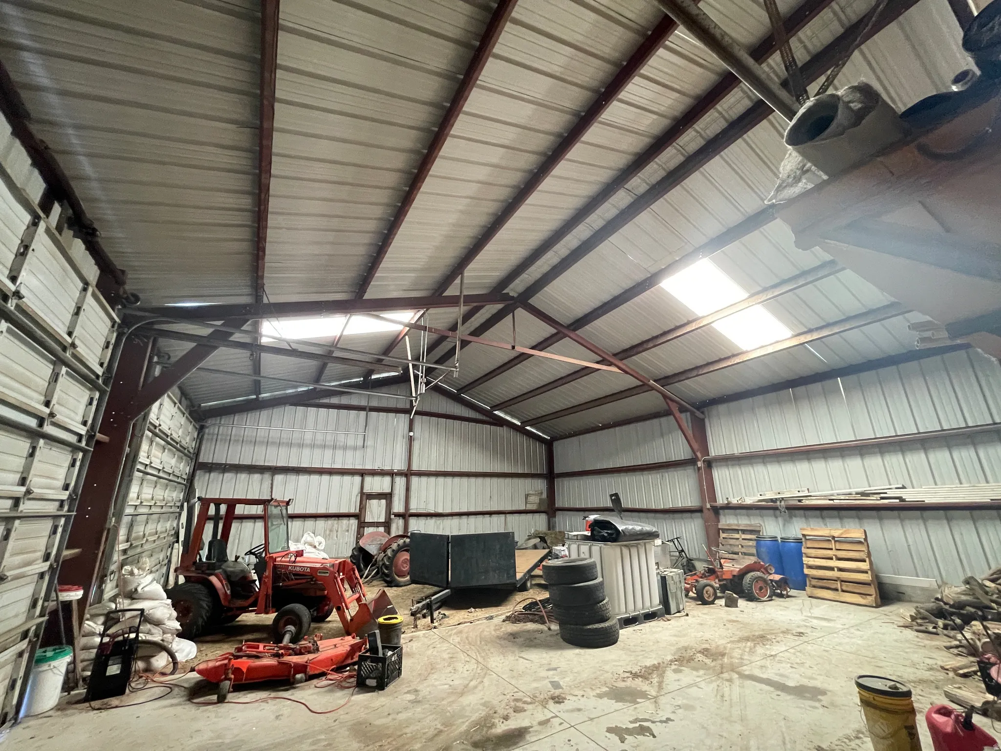 Spacious metal building featuring a corrugated metal roof, exposed steel truss system, and skylights for natural illumination