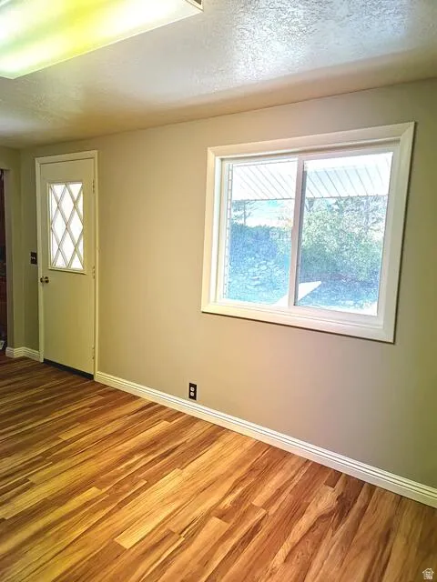 Wood-finish flooring throughout, featuring a white trim package, neutral wall paint, and a large window