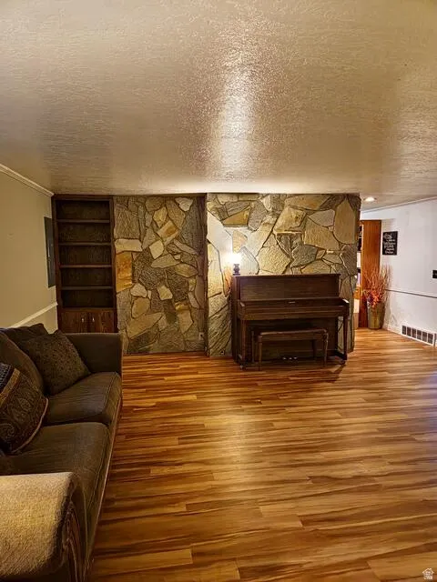 Living area featuring stone accent wall and wood-finish flooring