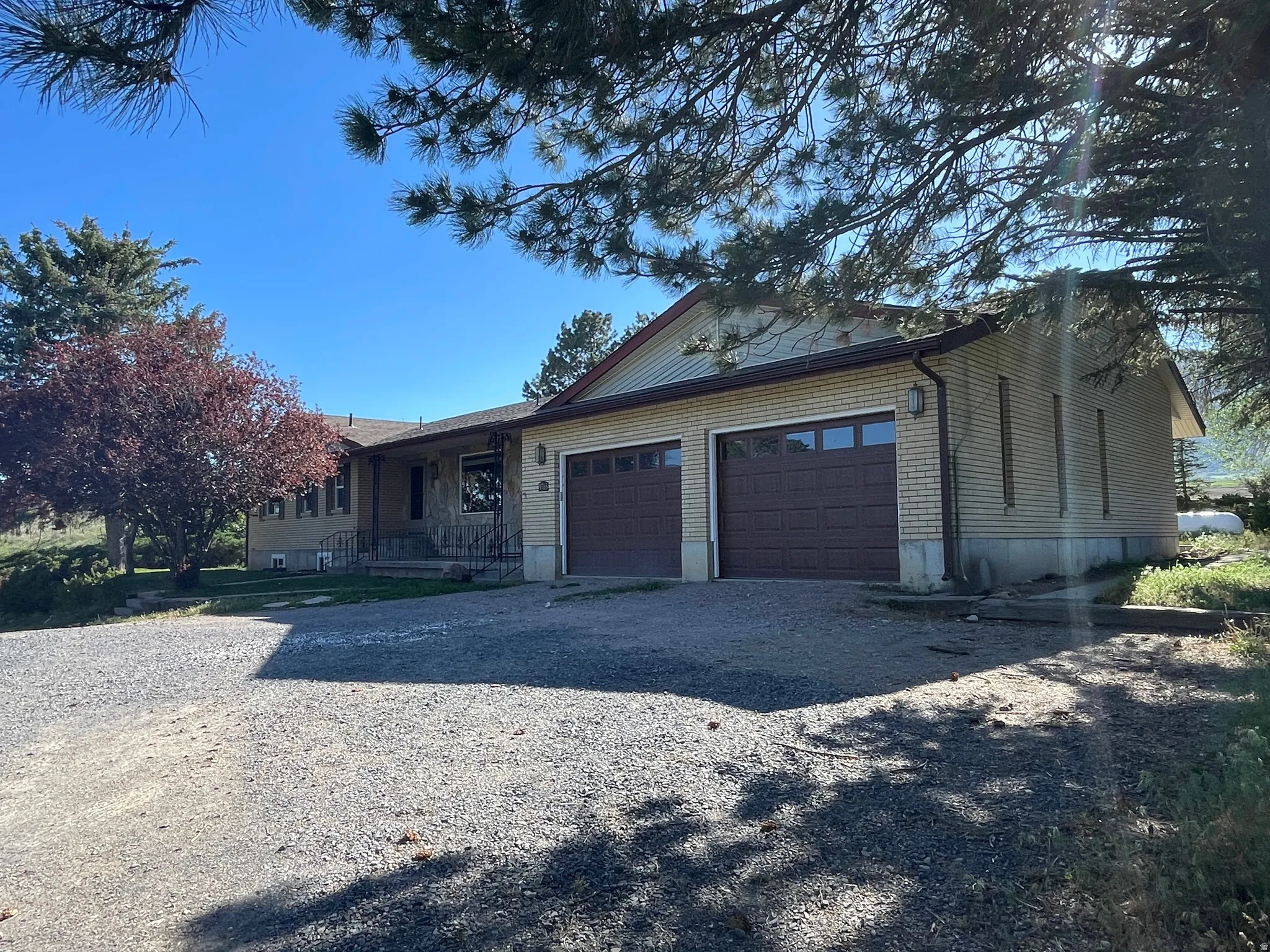Ranch-style residence featuring a two-car attached garage with individual brown panel doors and a light brick exterior