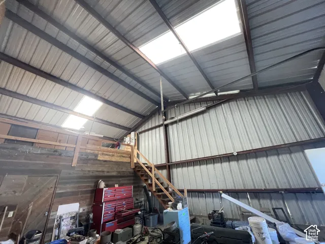Metal structure featuring a high ceiling, exposed beams, and multiple skylights