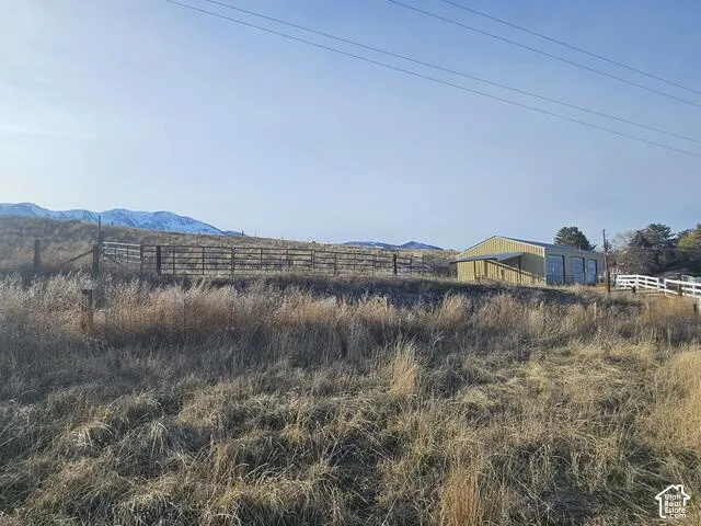Expansive open field with a metal-sided utility building featuring multiple bay doors