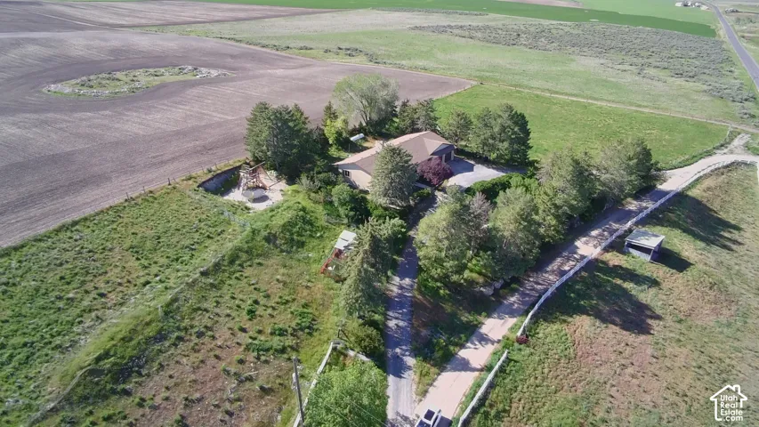Aerial perspective showcasing a single-story dwelling surrounded by agricultural land and mature trees