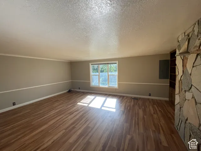 Spacious room featuring wood-finish flooring, a multi-pane window, and a stone-clad wall with built-in shelving
