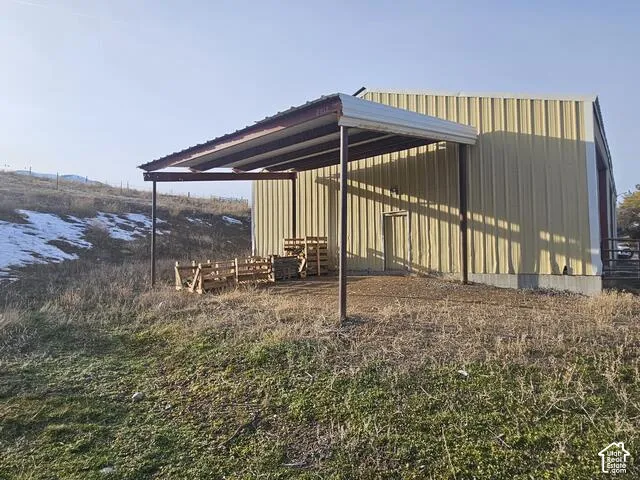 Metal-sided structure with a covered lean-to, a concrete foundation, and a single exterior door