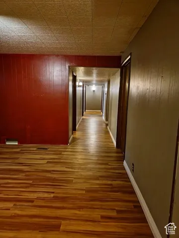 Hallway featuring wood-finish flooring, a textured ceiling, a red accent wall, and multiple doorways