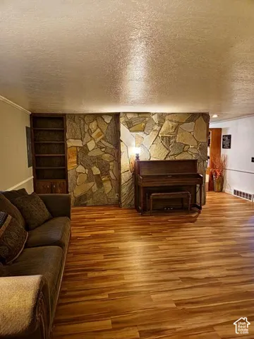 Living area featuring stone accent wall and wood-finish flooring