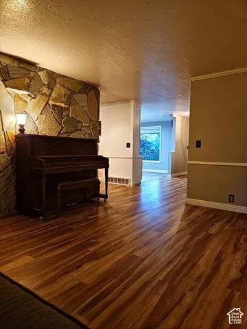 Interior space featuring wood-finish flooring, a stone-clad wall accent, and white baseboards