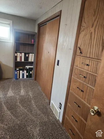 Carpeted room featuring a built-in wooden dresser with multiple drawers, a sliding closet door, and a built-in bookshelf